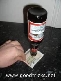 Money bill is carefully rolled up and should come out from under the beer bottle.