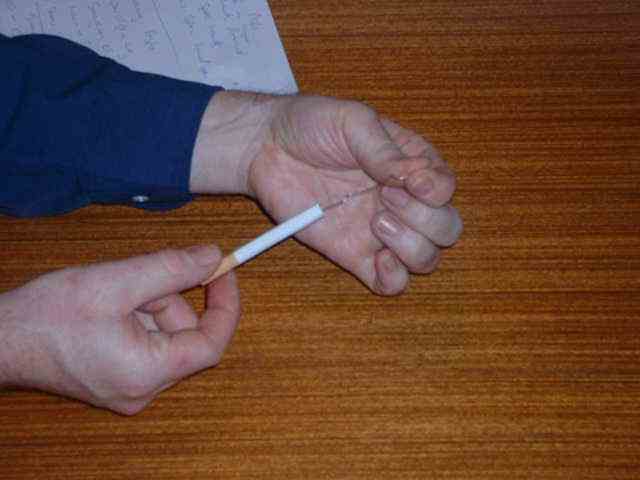 Insert the straightened paperclip into the cigarette.