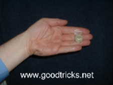 Photo shows coin attached to  hand with a length of clear adhesive tape. The tape  is very difficult for the audience to see, especially since your hand will be moving.