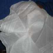 Spectators view of handkerchief, coin held with elastic band on other side is not visible.