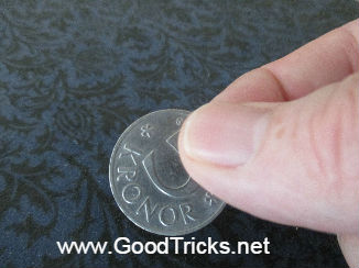 Coin being held between finger and thumb in preparation for a coin vanish trick.