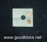 Square of paper shown with hole cut to size of small coin.