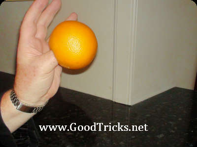 Push your thumb in the hole of the orange and rest the orange in your palm.