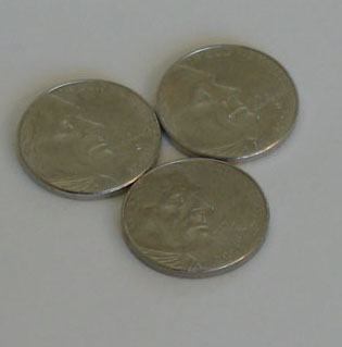 Three nickels are arranged side by side to form the base of a tower of coins.