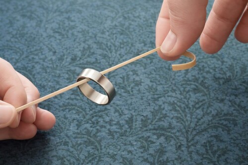 A finger ring is threaded onto the rubber band.