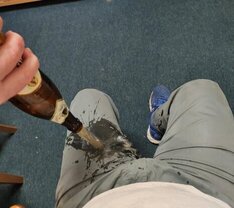 Image of upside down beer bottle spilling beer on trousers..