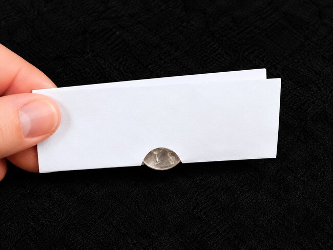 Folded paper with coin in the fold.
