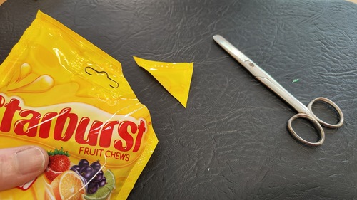 Cutting a triangular corner from a candy packet