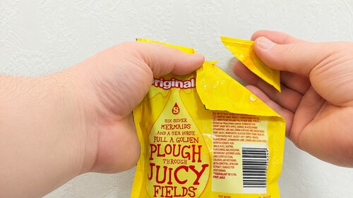 Hand bringing the torn corner over the packet