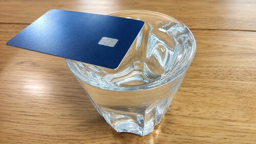 Card is placed on the edge of the rim of a glass of water.