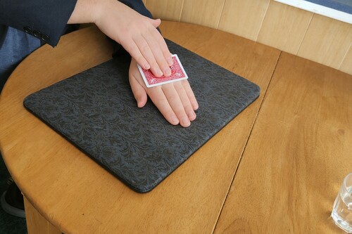 Playing card pressed gently onto the damp back of the magician's hand