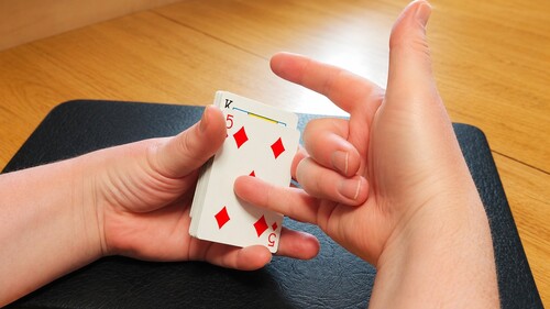 The little finger positioned behind the selected card