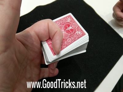 Deck of cards is shown held firmly between first and second curled fingers.