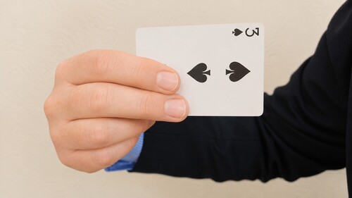 First and second fingers gripping the face of the playing cards