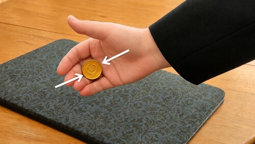 Fingers gently curling to hold the coin in Finger Palm