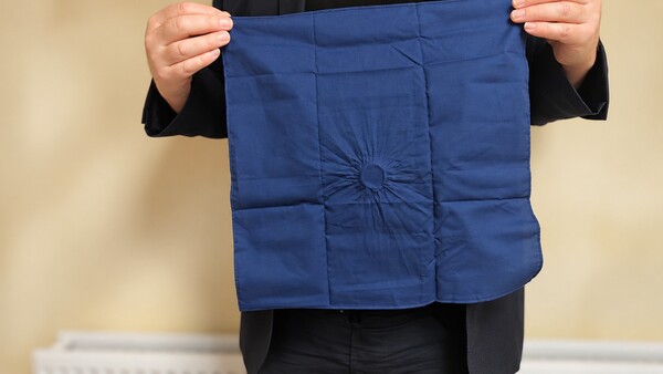 Handkerchief is spread open to reveal that a coin has seemingly disappered.