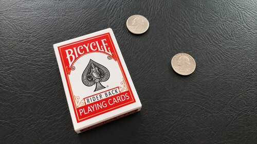 Deck of playing cards in its box beside two identical coins