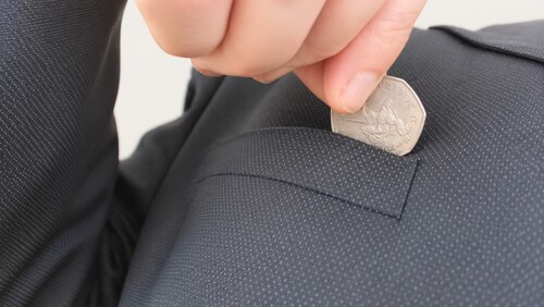Duplicate coin being casually placed into a pocket