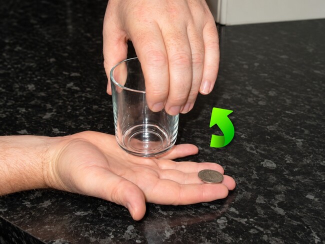 Coin being prepared to jump into a glass.
