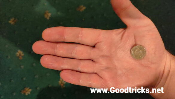 Coin is placed in palm of hand in fleshy part at base of thumb.
