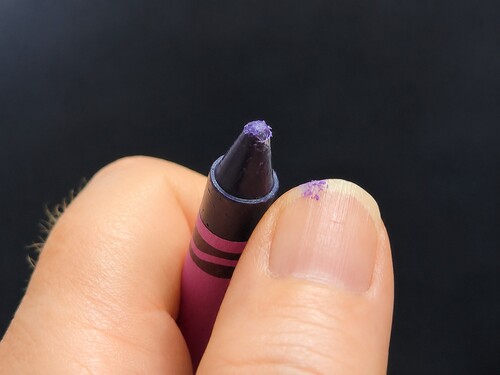 A tiny piece of crayon wax being scraped onto the thumbnail