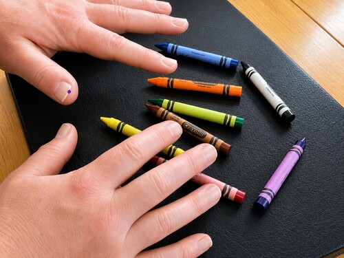 Hands making a natural magical gesture above a group of crayons
