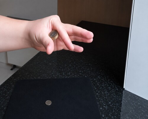 Two larger coins positioned together between the thumb and first finger