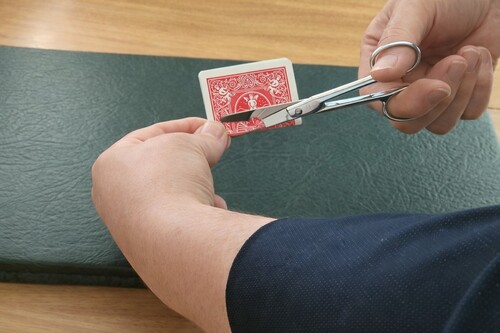 Playing card folded and prepared with a small central hole