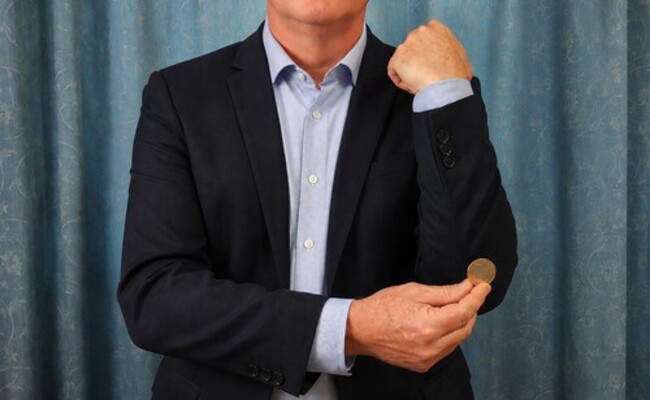 A coin being rubbed against the magician's elbow