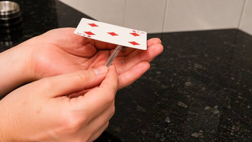 A pen being waved above and below a floating playing card