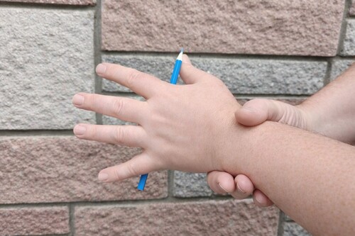 Audience view of a pencil apparently levitating beneath the magician's hand