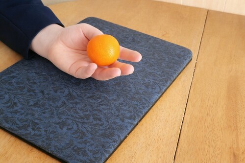 Thumb inserted into the hidden opening while the orange rests naturally in the palm