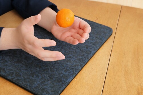 Orange appearing to levitate above a hand