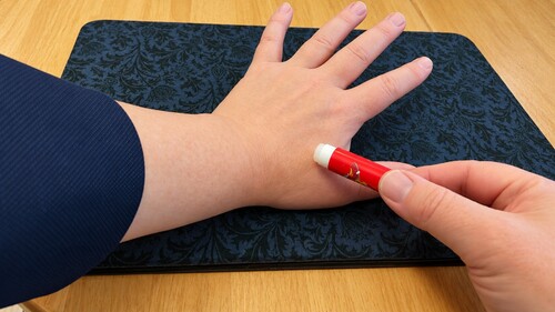 Applying a small amount of lip balm to the back of the hand