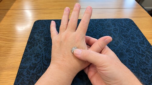 Small coin being pressed against the prepared area on the back of the hand