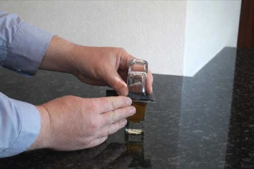 Water glass inverted above the whisky glass with a card between them