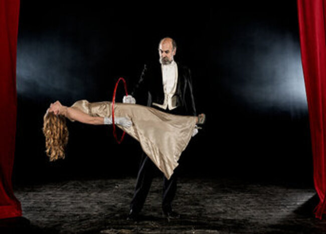 Magician apparently making an assistant float above a stage couch