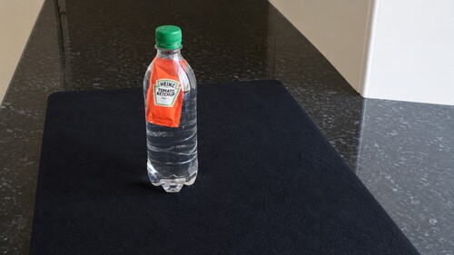 A sealed condiment sachet floating near the top of a bottle of water