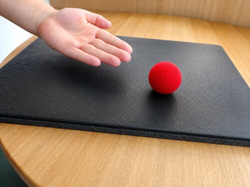 One sponge ball on the table beside the spectator's open palm
