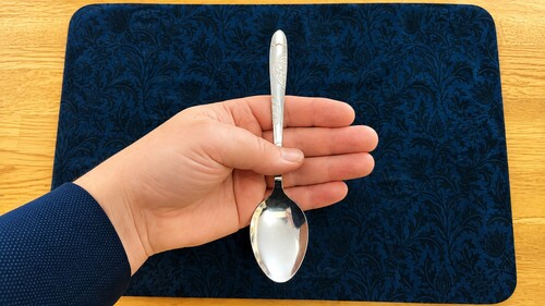 The real spoon bowl hidden behind the fingers while the gimmick is displayed