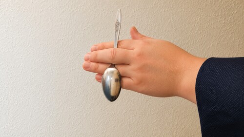 The real spoon bowl hidden behind the fingers.