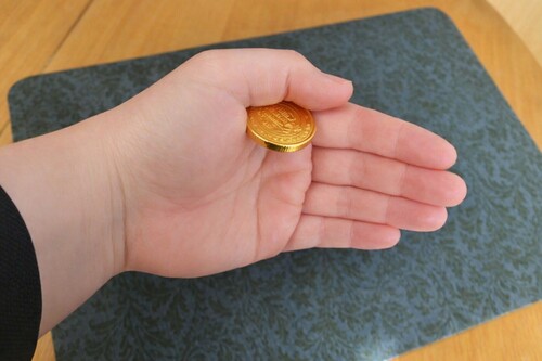 Coin positioned between the base of the thumb and side of the hand
