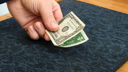 Dollar bill being handed back to a spectator while folded
