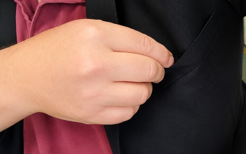 Magician pretending to place the torn piece of bill into a jacket pocket