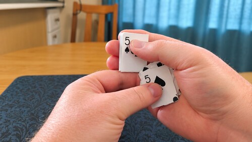 The torn card pieces being secretly exchanged for the folded duplicate