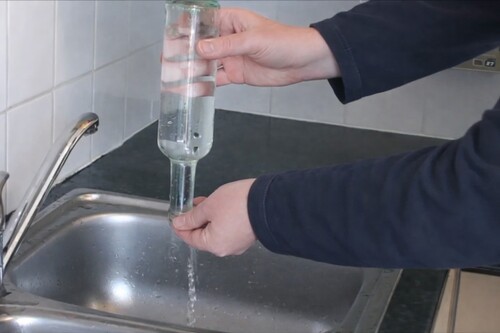 Clear plastic disc being placed over the mouth of the water bottle