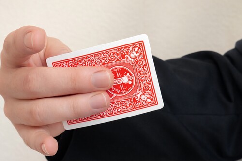 Two middle fingers positioned against the face of the playing card