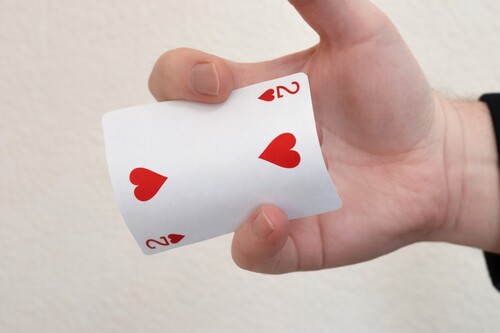 First and fourth fingers gripping the long edges of the playing card