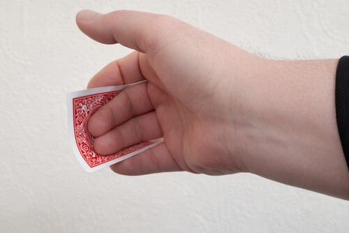 Playing card bending backward between the magician’s fingers