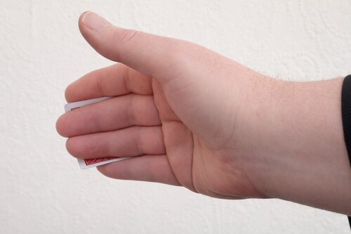 Middle fingers extending while the playing card moves behind the hand